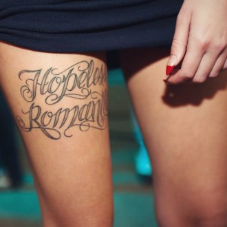 Женская татуировка надпись на бедре